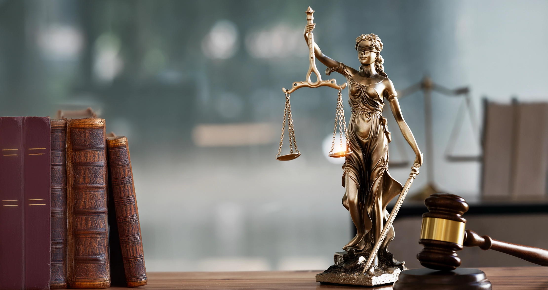 Justitia-Statue mit Waage und Richterhammer auf Schreibtisch